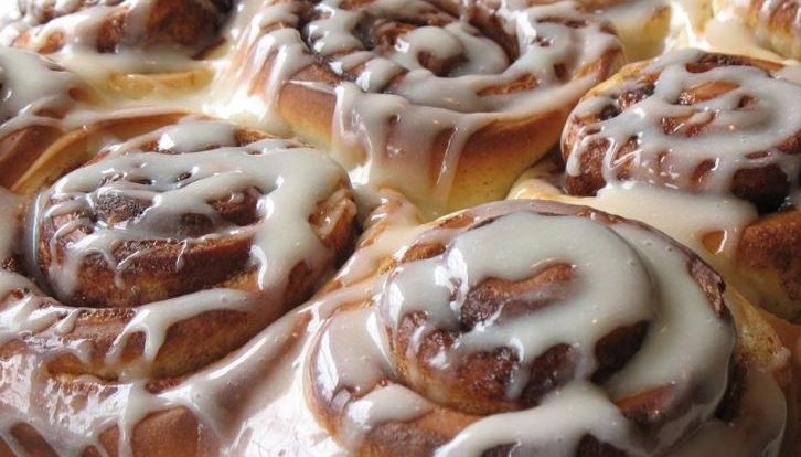 Homemade cinnamon rolls in a pan topped with creamy frosting