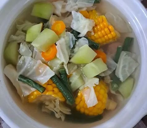 semangkuk sayur asem bening segar dengan jagung, labu siam, dan kacang panjang